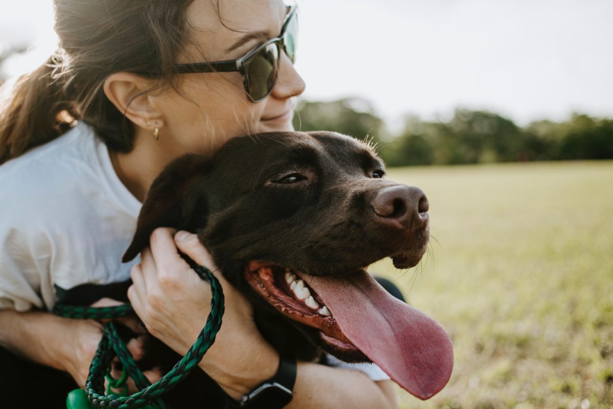 Woman and her dog on grassy field outdoors